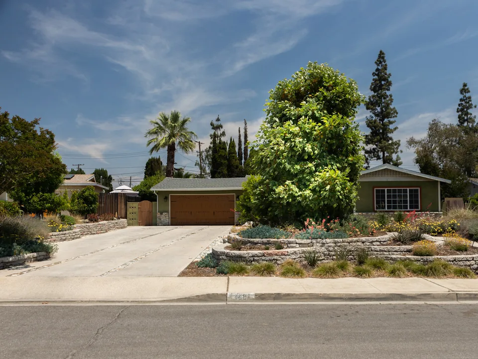Front yard with urbanites garden walls, drought-tolerant planting, and a permeable driveway beside a single-story home.